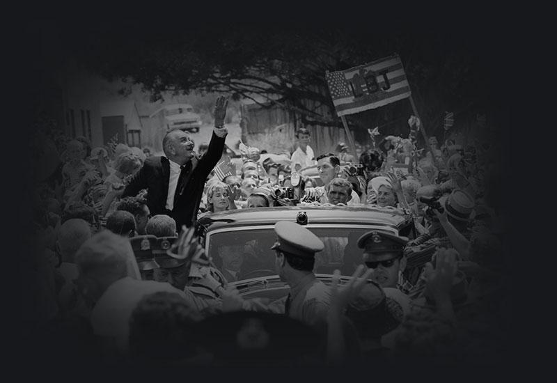 President of the United States of America, Lyndon B Johnson waiving from his motorcade surrounded by a crowd, 1966.