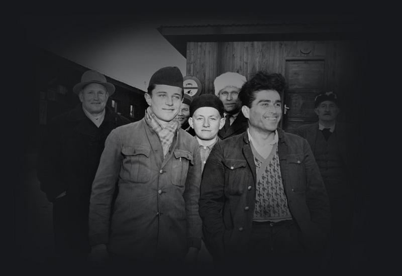 A group of 7 men in a displaced persons camp in Italy, smiling at the camera. 