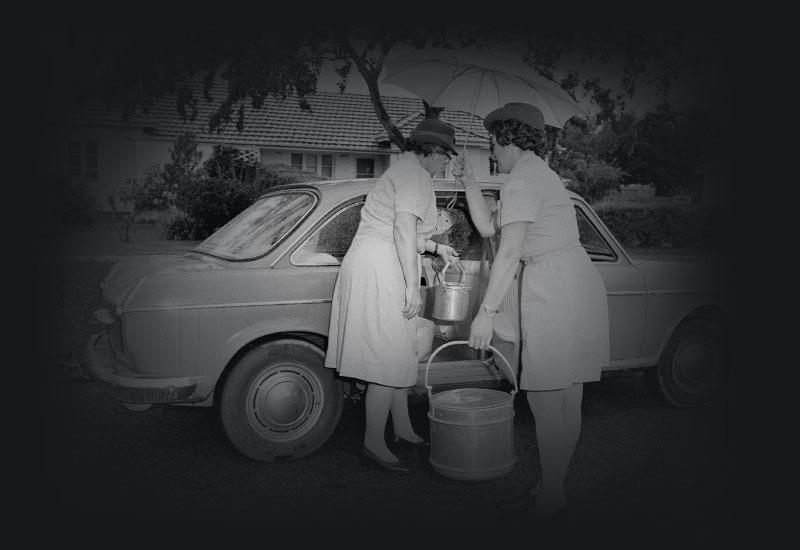 2 women placing prepared meals into a car.