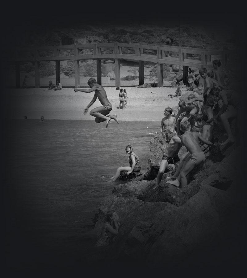 Children jumping off rocks into the sea.