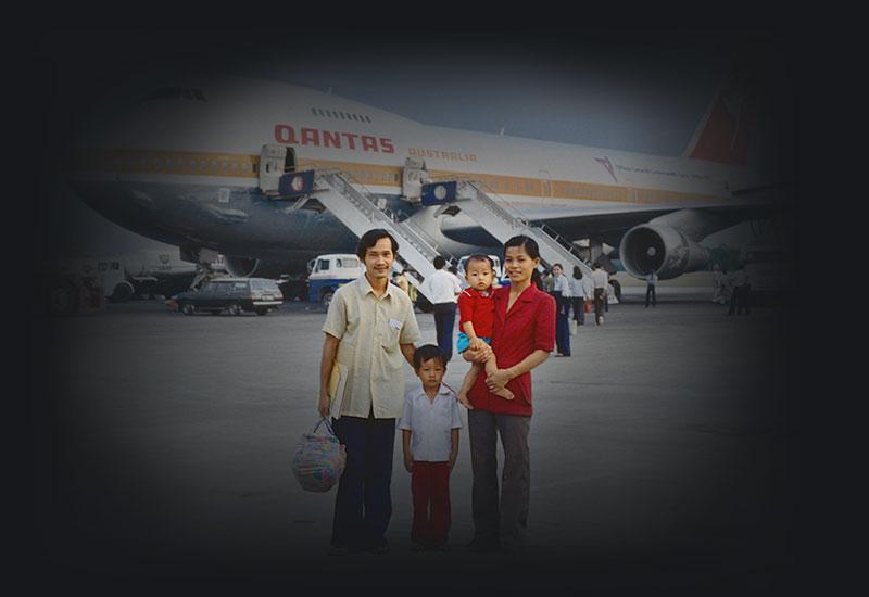 2 adults with young children standing on the tarmac with a Boeing 747 aircraft behind them.