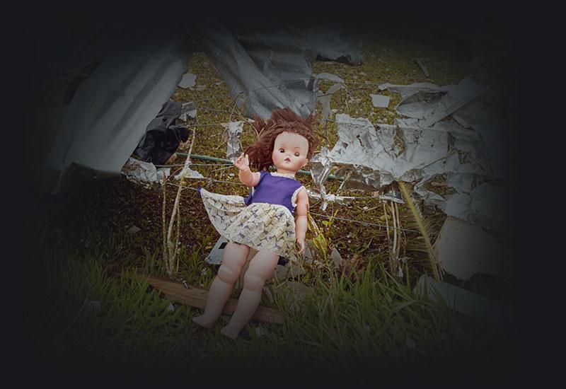 A doll amongst building material caught on a fence.