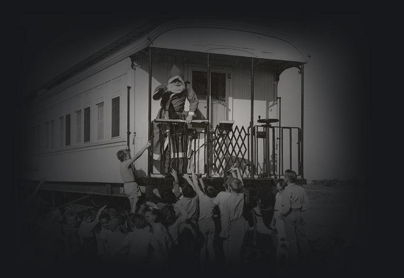 Children looking up at Santa and a railway carriage.