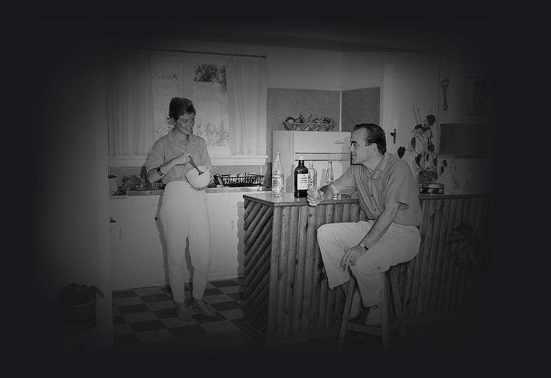 Josee stands in the kitchen while Jos sits at the kitchen bar.