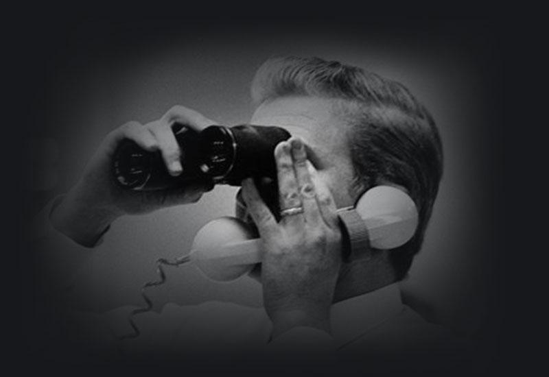 A man with a phone to his ear, looking through binoculars.