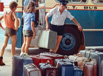 People boarding a bus beside rows of suitcases.