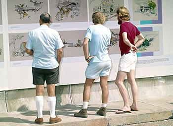 3 men looking at house drawings on a board.