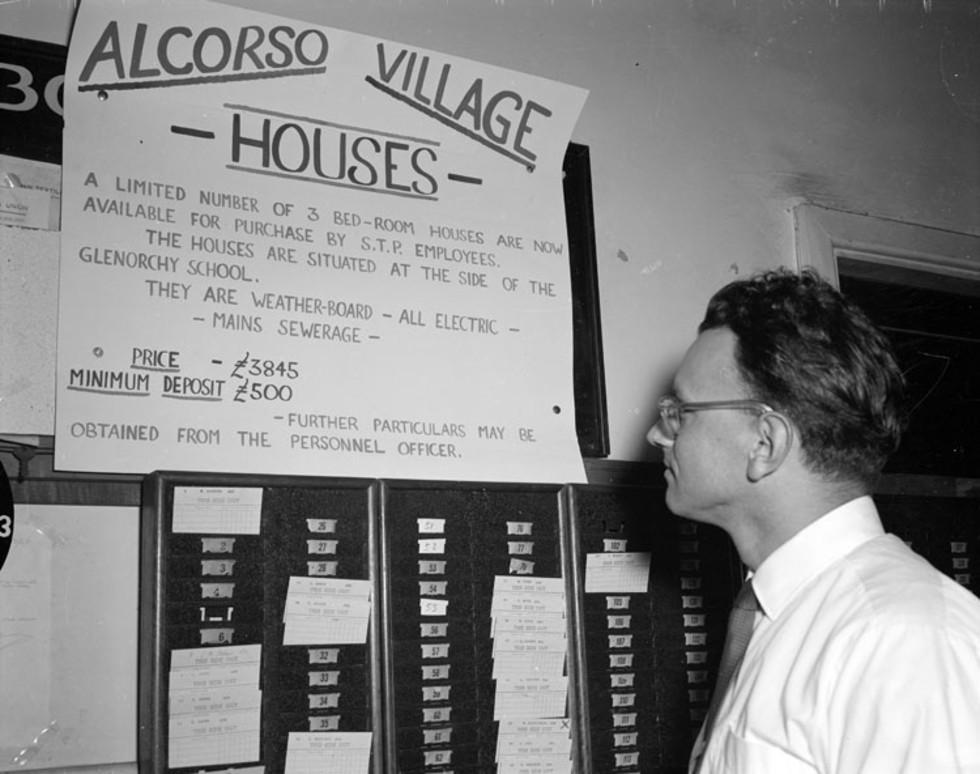 German migrant inspecting sign for Silk and Textile employee housing in Tasmania.