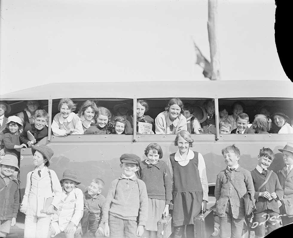 A group of school children standing beside a bus and looking out through the side windows. 