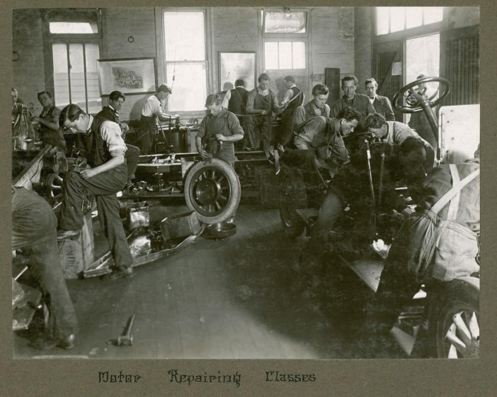 Men working in a workshop at a car repair class. 