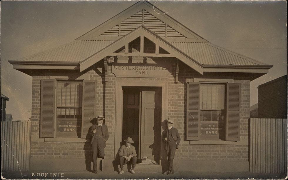 2 men standing and one seated at the entrance to the Western Australian Bank