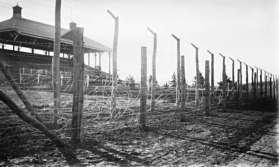 A grandstand behind a tall barbed wire fence.