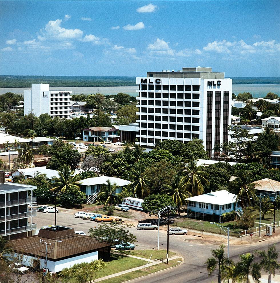 MLC building and houses amongst palm trees.