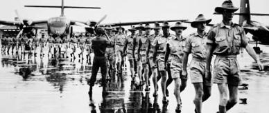 Soldiers marching along tarmac. RAAF Caribou aircraft in the background, Vietnam, 1972.