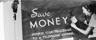 Telegraph office window display, text: 'Save MONEY – ADDRESS YOUR TELEGRAMS TO A TELEPHONE ADDRESS'.