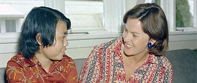 2 women turned toward each other smiling.