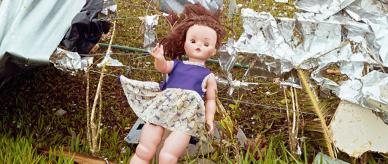 A doll amongst building material caught on a fence.