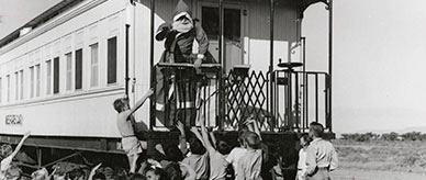 Children looking up at Santa aboard a railway carriage.