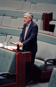 Independent MP Peter Andren standing with the House of Representatives green toned seating in the background.