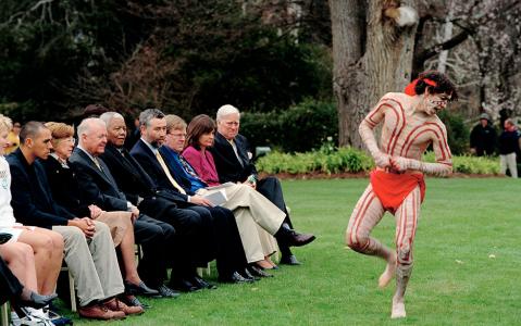 Governor-General Sir William Deane, Nelson Mandela and seated officials watch an Indigenous dancer on the lawn at Government House