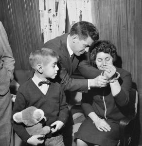 Renzo putting a gold watch on the wrist of his wife Antonia.