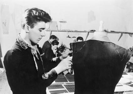 A young man working on a piece of clothing using a tailor's model.