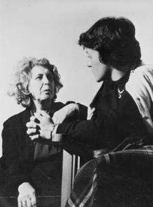 A young woman with her hands folded speaks to an older woman.