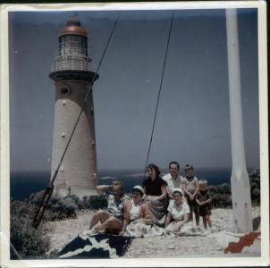 Voitre Marek and family sitting on the sand outside a lighthouse.