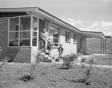 The Zevenbergen family standing on the front steps of their brick house.