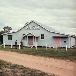 A light blue painted timber hall (building) with corrugated roof and pink doors.