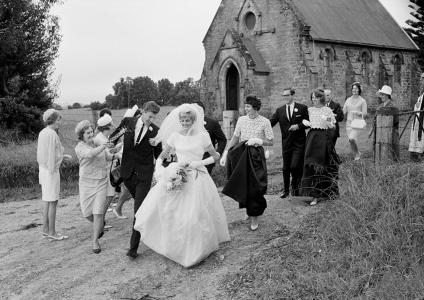 Married couple with their wedding party leaving a country church.