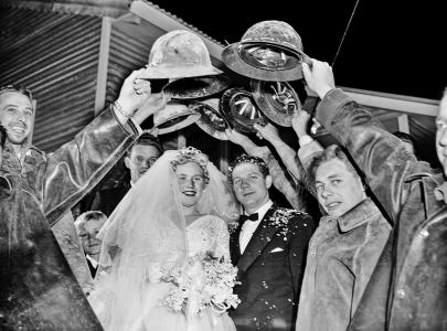 Workmen forming a guard of honor with their hard-hats for a bride and groome .