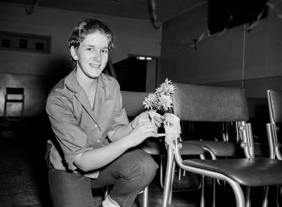 A woman fixing flowers to a chair.