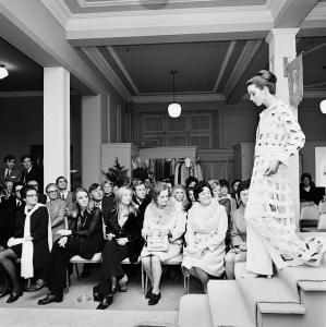 A woman descending stairs at Georges fashion show wearing a dress by Jean Patou.