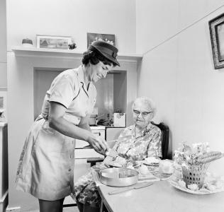 A Red Cross worker prepares a meal for a pensioner in her home.