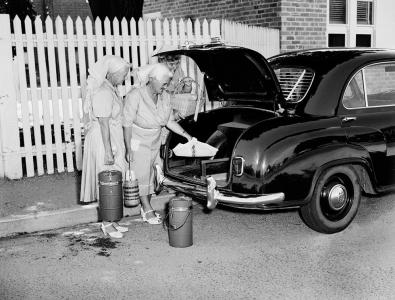 3 women placing prepared meals into the boot of car.