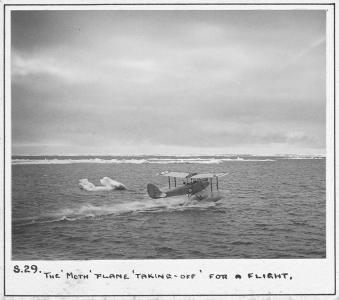 Gypsy moth float biplane taking off from water. 