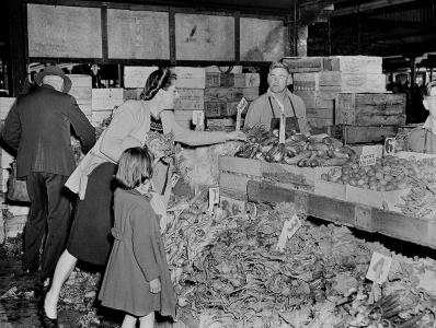 A woman and child shopping for vegetables at a fruit and vegetable market.