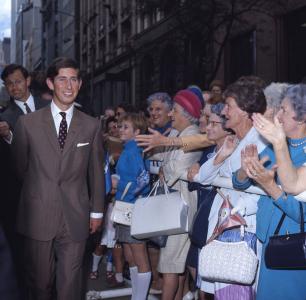 A group of ladies smile as Prince Charles walks past while meeting the crowds.