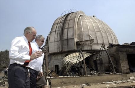 John Howard and Ian Chubb walking in front of the burned remains of Mount Stromlo Observatory. 