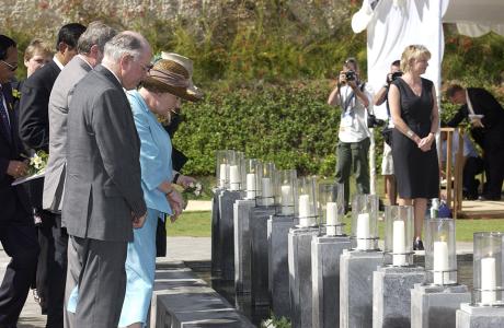 John and Janette Howard bowing their heads in front of a row of memorial stones and candles.