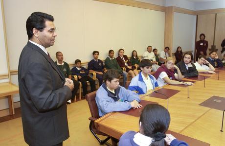 Senator Aden Ridgeway talking to a room full of students in a Parliament House boardroom. 