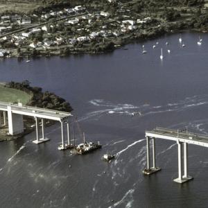 River craft anchored between the remaining sections of the bridge.