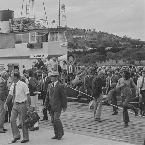 Passengers depart a crowded ferry docked beside a wharf.