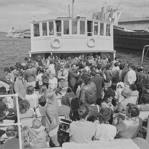 People on the open deck of a crowded ferry.