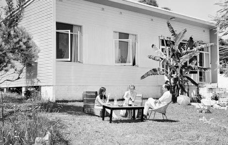 Josee and friends sit around a coffee table on the lawn beside his modern timber house.