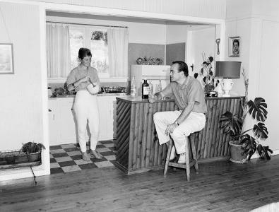 Josee stands in the kitchen while Jos sits at the kitchen bar.